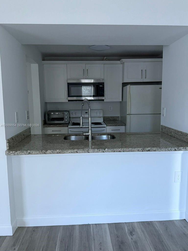 6955 Northwest 186th Street, Unit F209 Hialeah, FL 33015 - Photo 3 of 14 a view of kitchen with stainless steel appliances granite countertop a sink a stove and a microwave