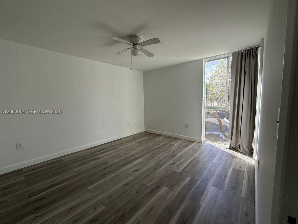 6955 Northwest 186th Street, Unit F209 Hialeah, FL 33015 - Photo 6 of 14 an empty room with wooden floor fan and windows