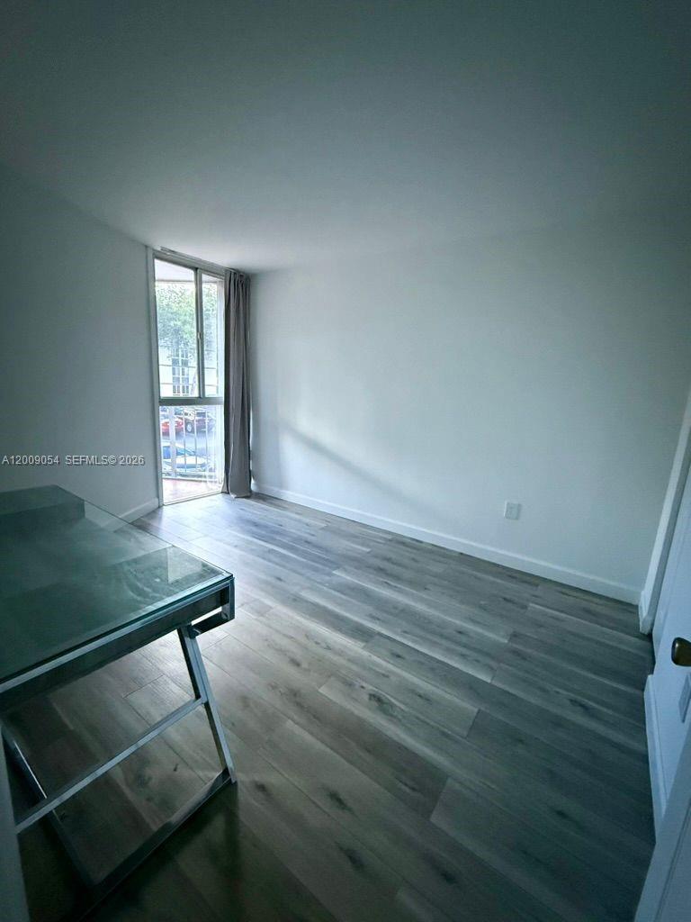 6955 Northwest 186th Street, Unit F209 Hialeah, FL 33015 - Photo 10 of 14 a view of an empty room with wooden floor and a window