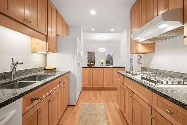 a kitchen with stainless steel appliances granite countertop a sink a stove and a wooden cabinets