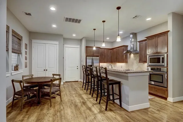 a kitchen with a table chairs wooden floors and a view of living room