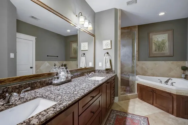 a bathroom with a granite countertop double vanity sink and a mirror