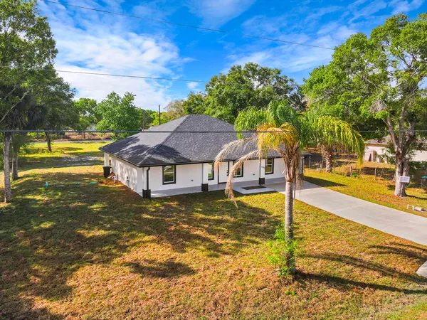a view of swimming pool with lawn chairs and large trees