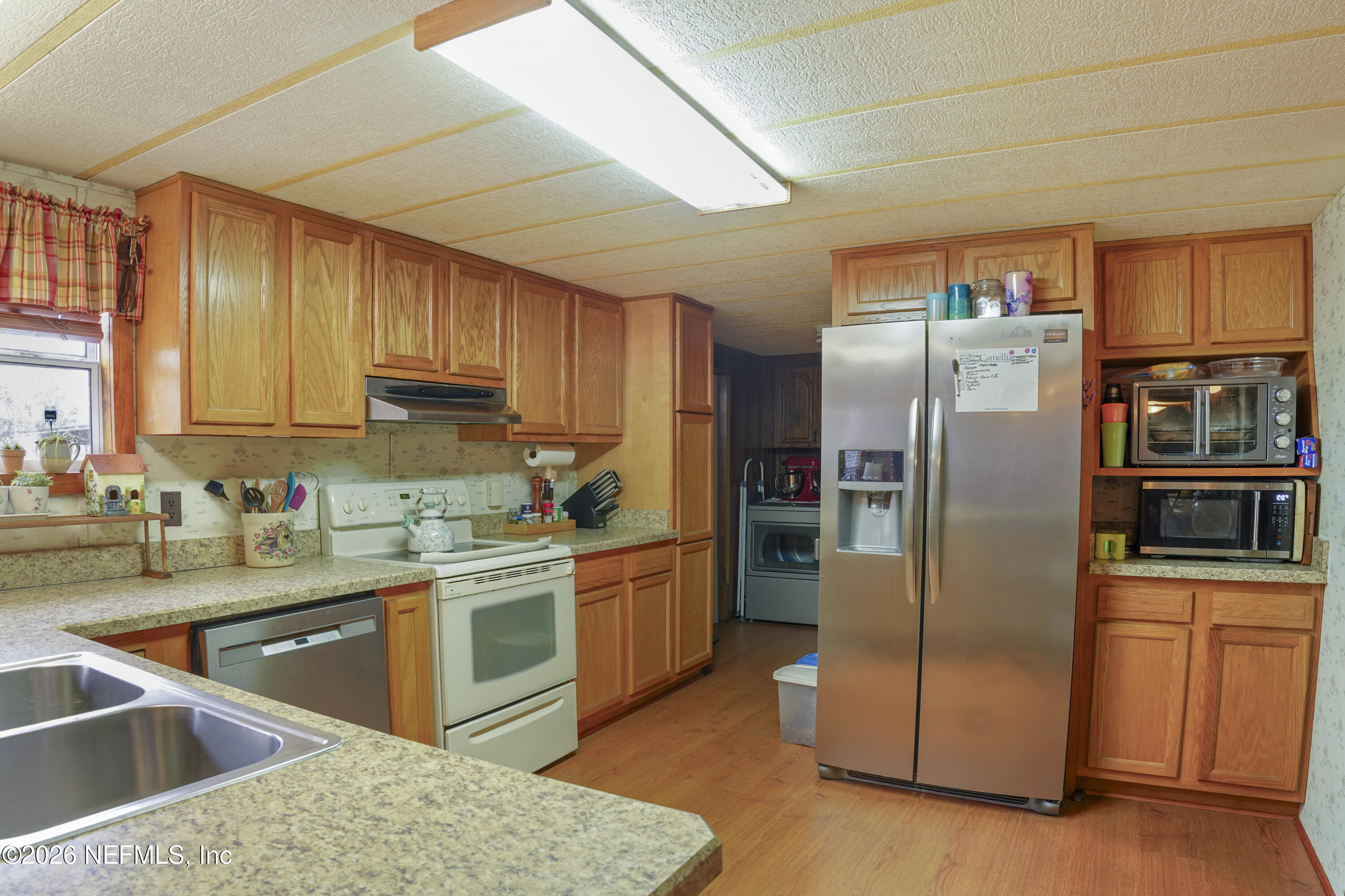 10697 County Road 127 Sanderson, FL 32087 - Photo 30 of 40 a kitchen with stainless steel appliances granite countertop a refrigerator a sink dishwasher a stove with wooden cabinets and floor