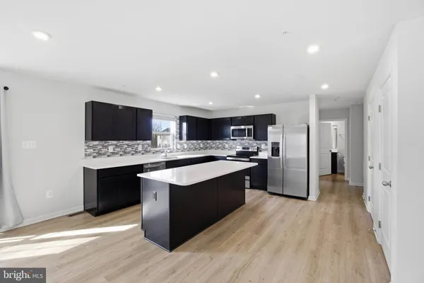 a large kitchen with stainless steel appliances kitchen island granite countertop a stove and a sink