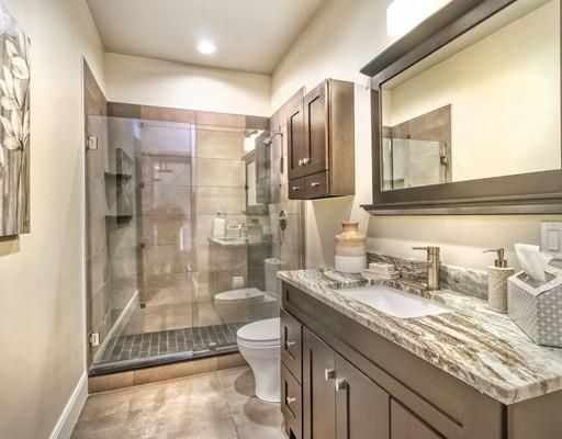 a bathroom with a granite countertop sink a toilet a mirror and shower