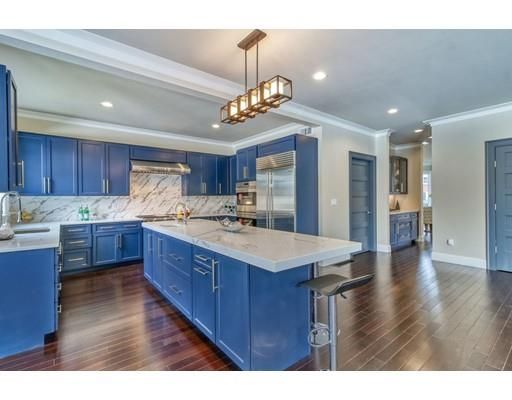 a kitchen with stainless steel appliances granite countertop wooden floors wooden cabinets a center island and chairs