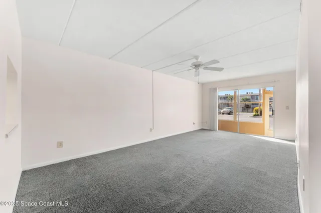 an empty room with ceiling fan and window