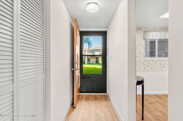 a view of a hallway with wooden floor and a bathroom