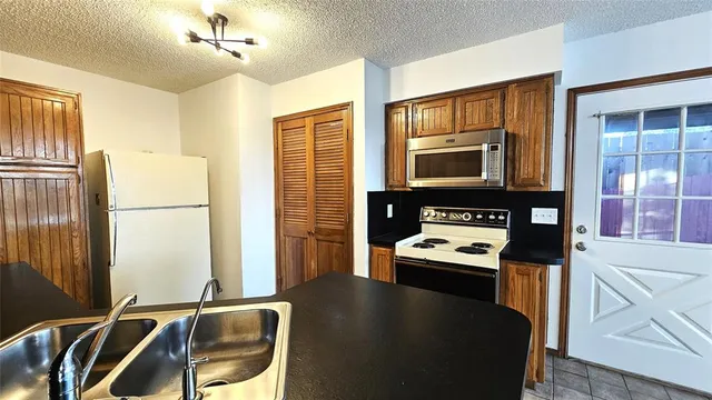 a kitchen with stainless steel appliances granite countertop a refrigerator a stove and a sink with wooden floor