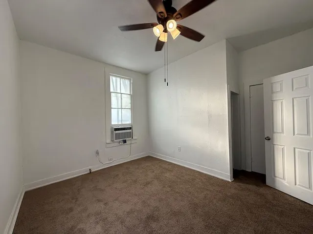 an empty room with windows and fan