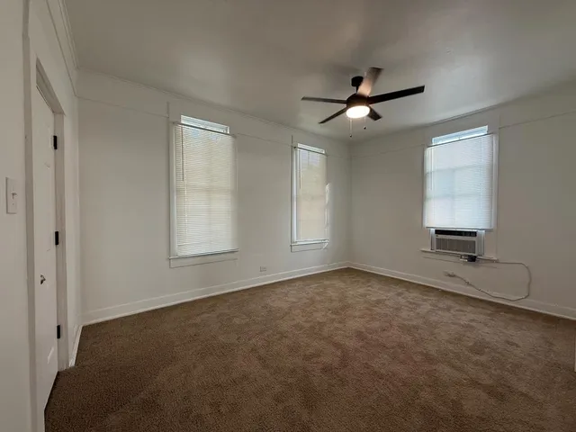 an empty room with windows and fan