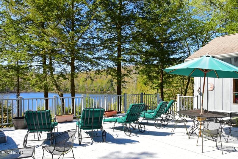 57 Hayes Pond Road Otis, MA 01253 - Photo 9 of 36 a view of a patio with a table and chairs under an umbrella with wooden fence
