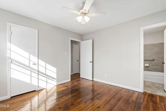 a view of an empty room with window and wooden floor