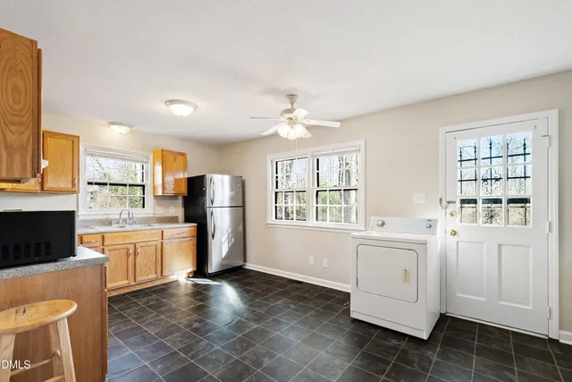 a large white kitchen with granite countertop a sink a window and stainless steel appliances