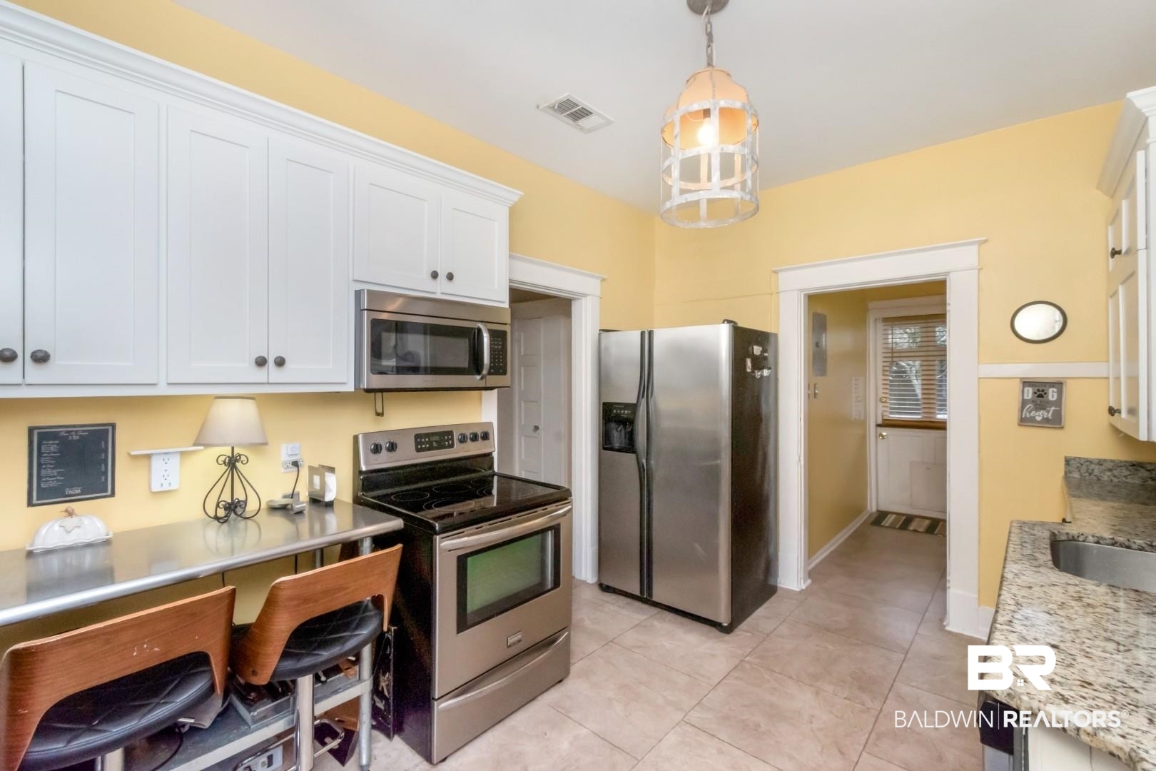 135 Silverwood Street Mobile, AL 36607 - Photo 9 of 32 Kitchen with stainless steel appliances, decorative light fixtures, white cabinetry, and light tile patterned floors