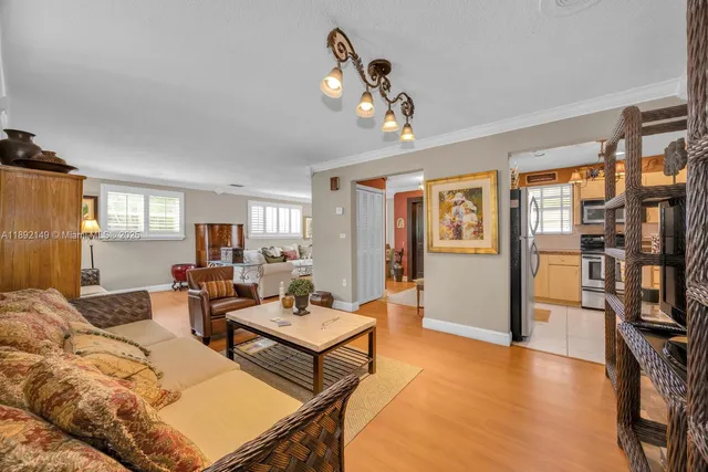 a living room with furniture a bookshelf and kitchen view