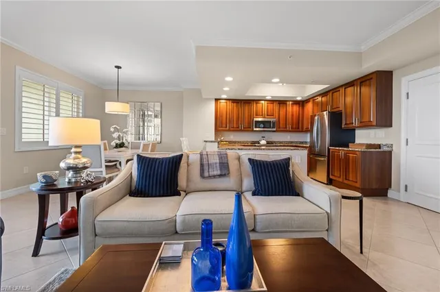 a living room with stainless steel appliances furniture a rug and a kitchen view