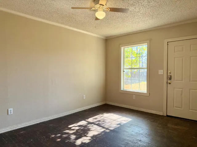 an empty room with wooden floor fan and windows