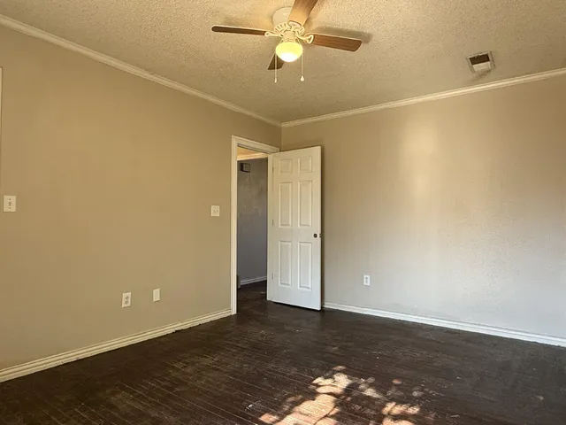 an empty room with wooden floor and fan