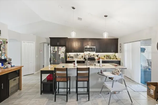 a kitchen with stainless steel appliances kitchen island granite countertop a dining table and chairs
