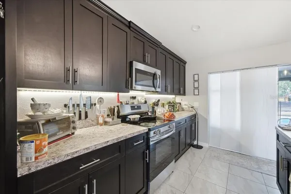 a kitchen with granite countertop a sink dishwasher stove and cabinets