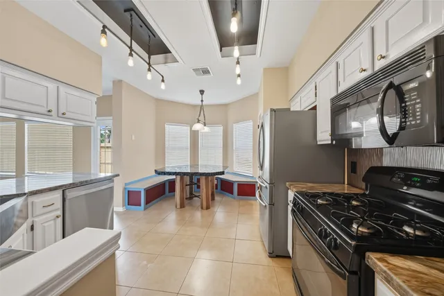 a kitchen with stainless steel appliances granite countertop a stove a refrigerator a sink a dining table and chairs with wooden floor