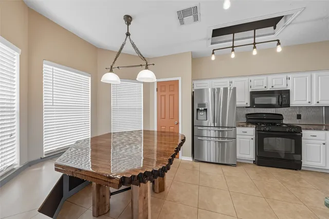 a kitchen with stainless steel appliances kitchen island granite countertop a refrigerator a stove and a sink