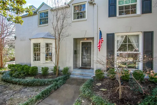 a view of a brick house with large windows and plants