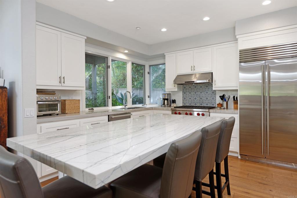 1739 Sienna Canyon Drive Encinitas, CA 92024 - Photo 5 of 29 a kitchen with a stove a sink a kitchen island a stove a dining table and chairs