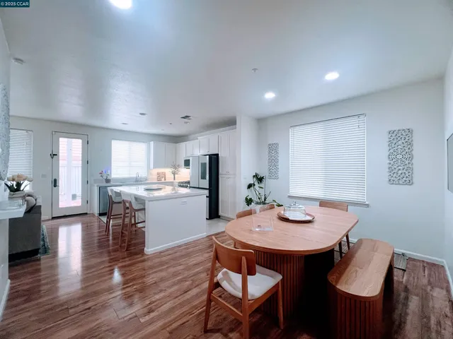 a kitchen with a dining table chairs and wooden floor