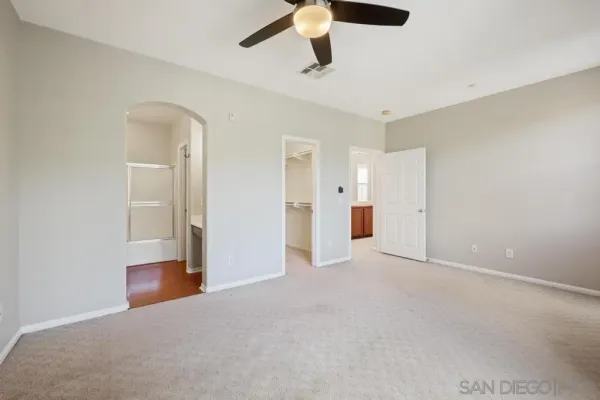 an empty room with chandelier fan and stainless steel appliances