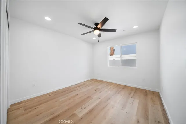 an empty room with wooden floor ceiling fan and windows