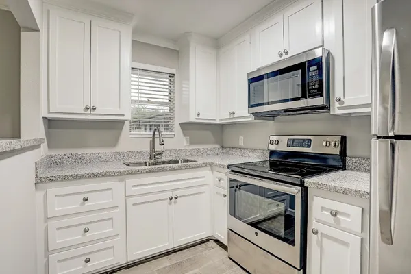 a kitchen with granite countertop white cabinets stainless steel appliances and a sink