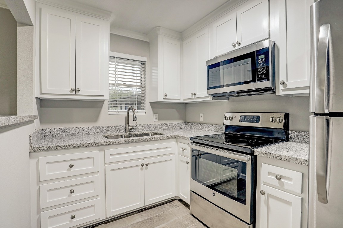 a kitchen with granite countertop white cabinets stainless steel appliances and a sink