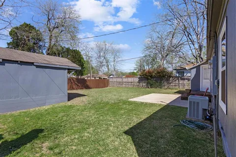 a view of a backyard with potted plants and large trees