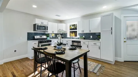 a kitchen with stainless steel appliances kitchen island granite countertop a table chairs and a refrigerator