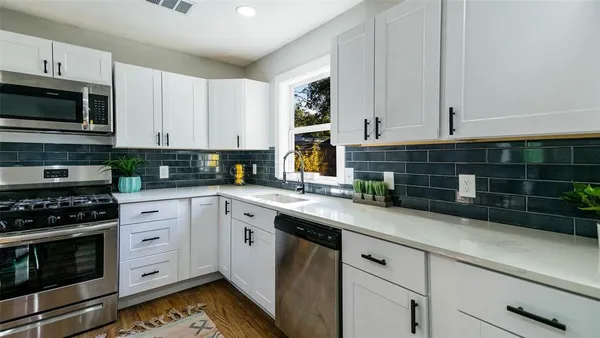 a kitchen with stainless steel appliances white cabinets and a stove a oven with wooden floor