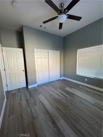 an empty room with wooden floor fan and windows