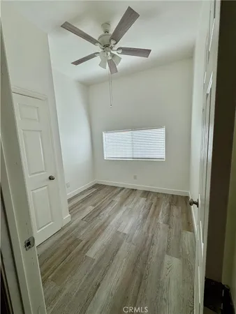 en empty room with wooden floor and fan