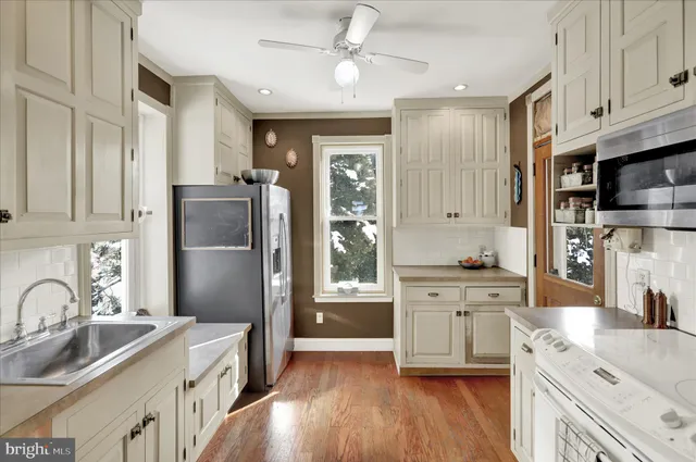 a kitchen with stainless steel appliances granite countertop a refrigerator a sink dishwasher a stove and white countertops with wooden floor