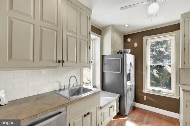 a kitchen with stainless steel appliances granite countertop a refrigerator a sink a stove and white cabinets with wooden floor