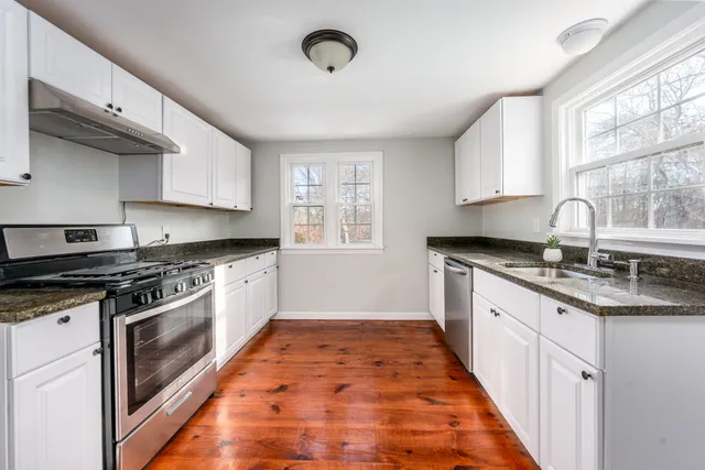 a kitchen with granite countertop stainless steel appliances a stove a sink and a window