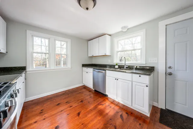 a kitchen with granite countertop white cabinets and wooden floor