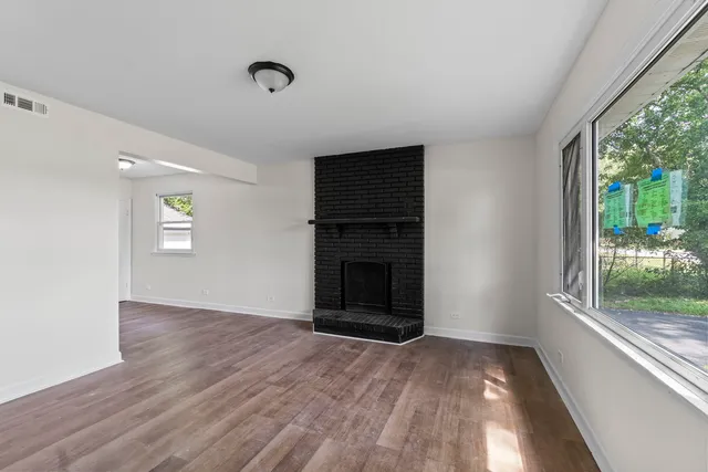 an empty room with windows and fireplace