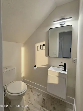 a bathroom with a toilet a sink and mirror