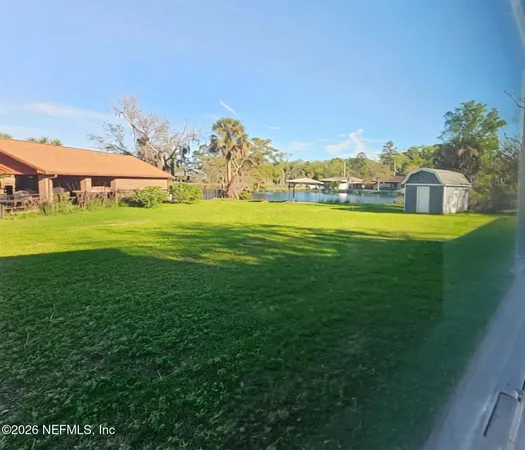 a view of a big yard with table and chairs under an umbrella