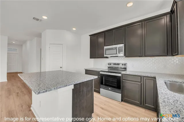 a kitchen with stainless steel appliances granite countertop a sink stove and microwave