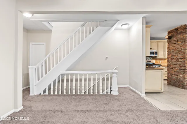 a view of an empty room with chandelier fan and windows