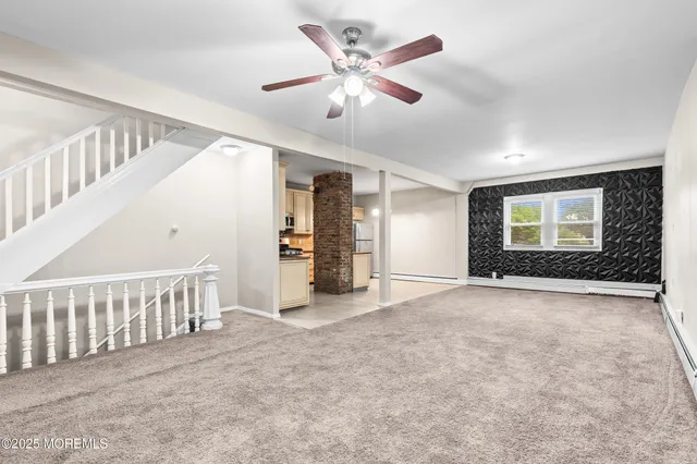 an empty room with chandelier fan and windows